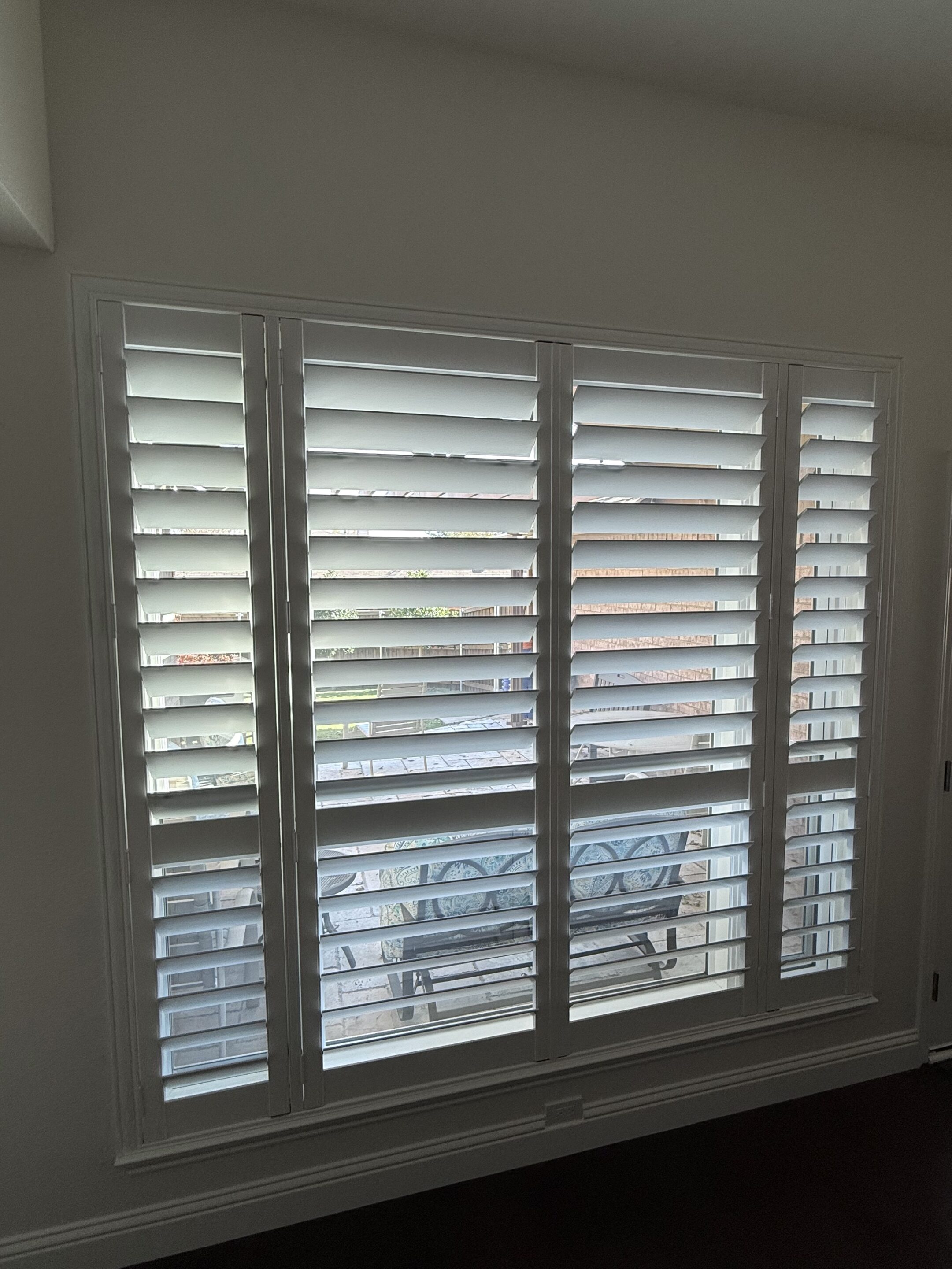 Four-panel white plantation shutters with wide louvers in a Rockwall, Dallas home